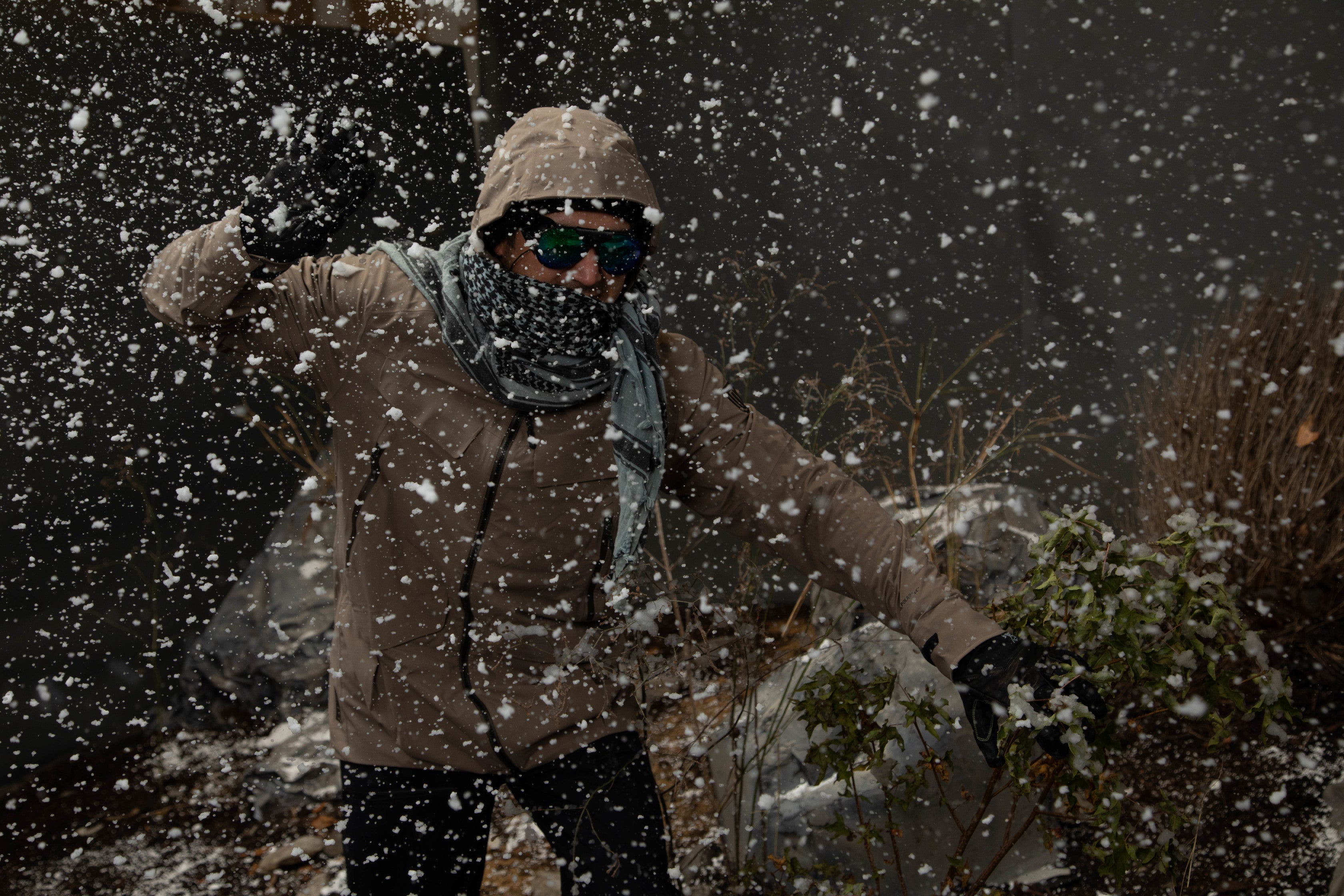 man wearing winter attire and sunglasses while it snows